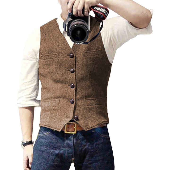 Mann in brauner Tweed-Weste, weißem Hemd, Jeans, hält Kamera. Vintage Herrenmode.