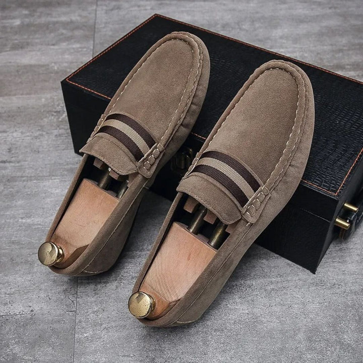 Braune Wildleder-Loafer mit Holzschuhspanner auf grauem Boden, elegante Herrenschuhe.