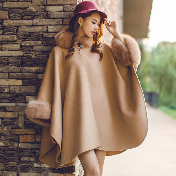 Frau in beigem Wollponcho mit Kunstpelz, rotem Hut, Herbstmode, stilvoll, elegant.