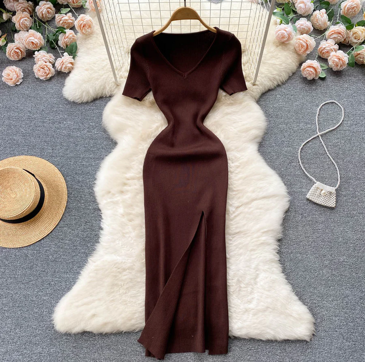 Braunes Strickkleid mit V-Ausschnitt, Kurzarm, Schlitz, auf weißem Fellteppich, elegantes Design.