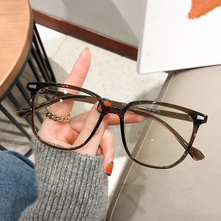 Braune, eckige Brille aus Kunststoff, modisch, auf grauem Hintergrund gehalten.