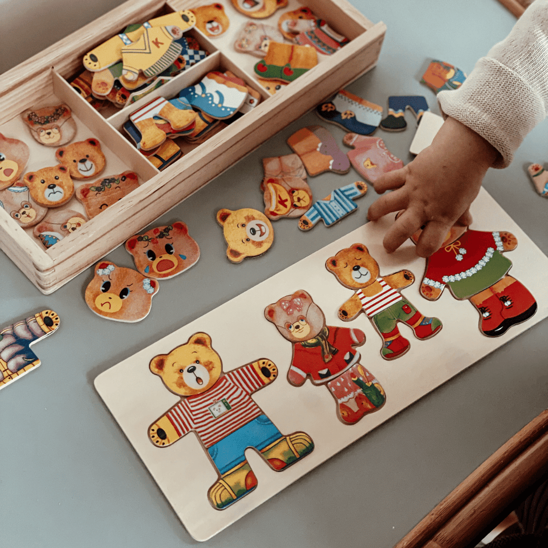 Kinderspielzeug Holzpuzzle Bären, bunte Kleidung, Hand eines Kindes, pädagogisches Spielzeug.