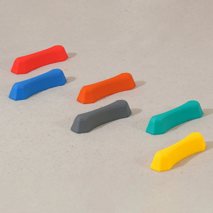 Bunte Kunststoff-Balanciersteine auf Sandboden, ideal für Kinderbalance-Übungen.