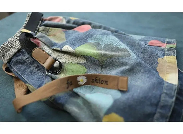 Bunte Jeans-Shorts mit Blumenmuster, elastischem Bund und Gürtel, modische Sommerkleidung.