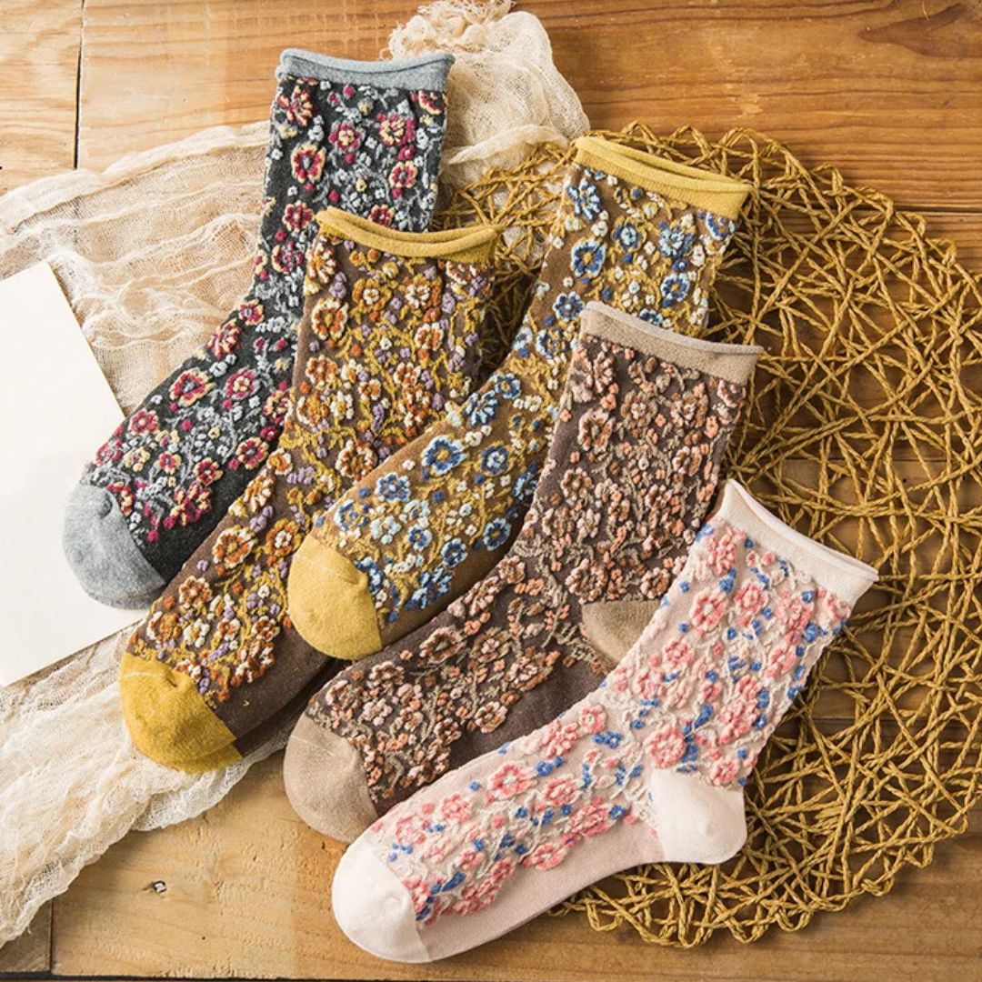 Bunte Blumenmuster-Socken aus Baumwolle auf Holztisch, modische Damenstrümpfe.
