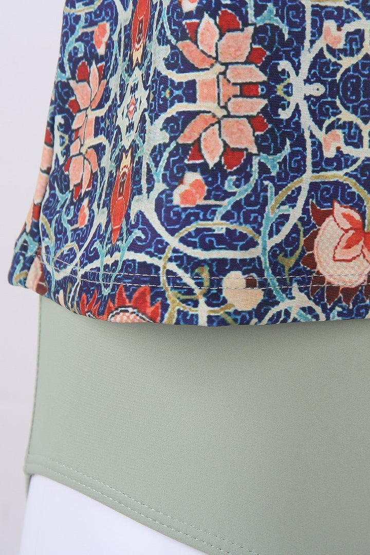 Bunte gemusterte Bluse mit floralen Motiven auf grünem Hintergrund, Damenmode, elegant.