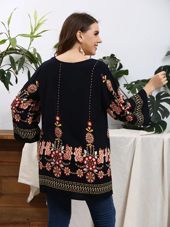 Frau in schwarzer bestickter Tunika mit buntem Blumenmuster, lässige Mode, Rückansicht.