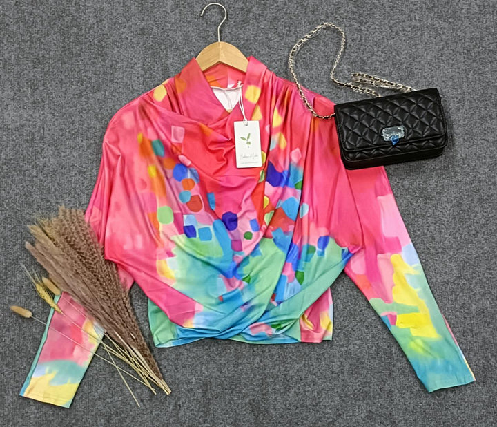 Buntes Damenoberteil mit abstraktem Muster, schwarze Umhängetasche, Trockenblumen, Kleiderbügel.