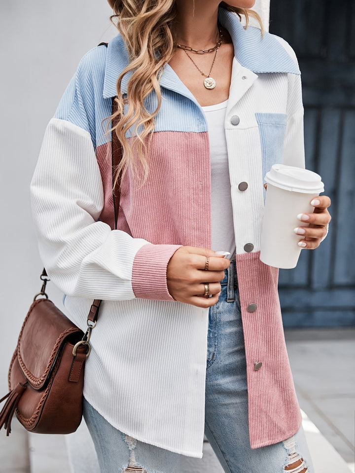 Frau in pastellfarbener Cordjacke mit Kaffeebecher und brauner Umhängetasche.