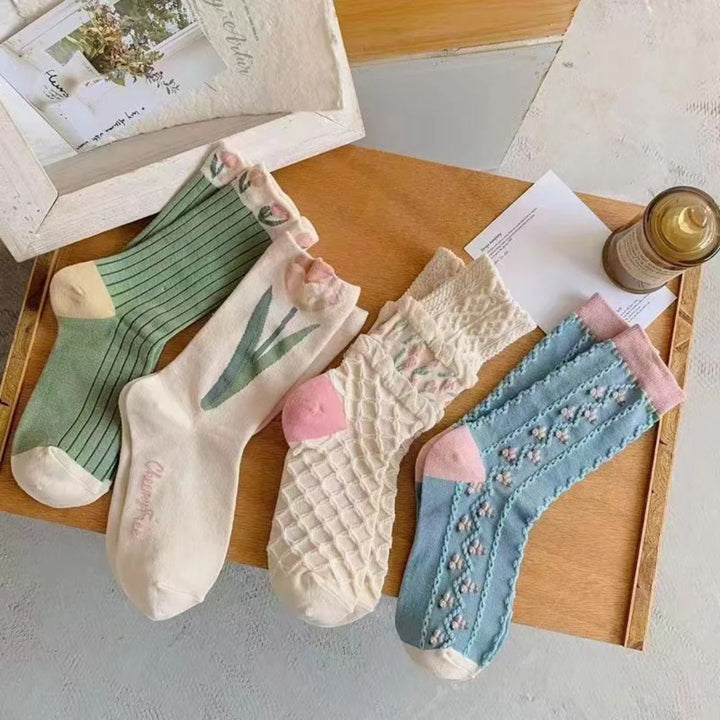 Vier Paar bunte Baumwollsocken auf Holztablett, gestreift und gemustert, für Damen.