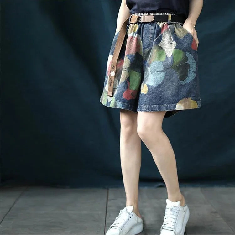 Frau trägt blauen Jeansrock mit Blumenmuster, Gürtel und weißen Sneakers.