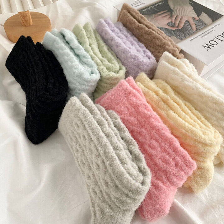 Bunte, flauschige Wollsocken in verschiedenen Farben auf weißem Hintergrund.