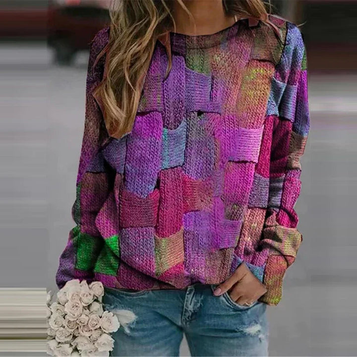 Frau in bunter Patchwork-Bluse, hält weiße Rosen, trägt blaue Jeans.
