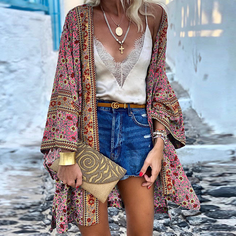 Frau in bunter Kimono-Jacke, Spitzen-Top, Jeansshorts, goldene Accessoires, Sommermode.