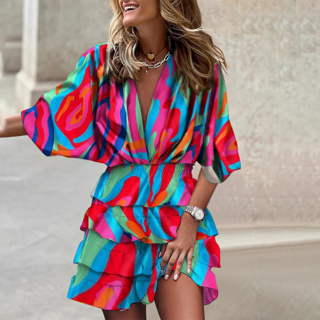 Frau in buntem, gemustertem Sommerkleid mit Rüschen, lächelnd, modisch, draußen.