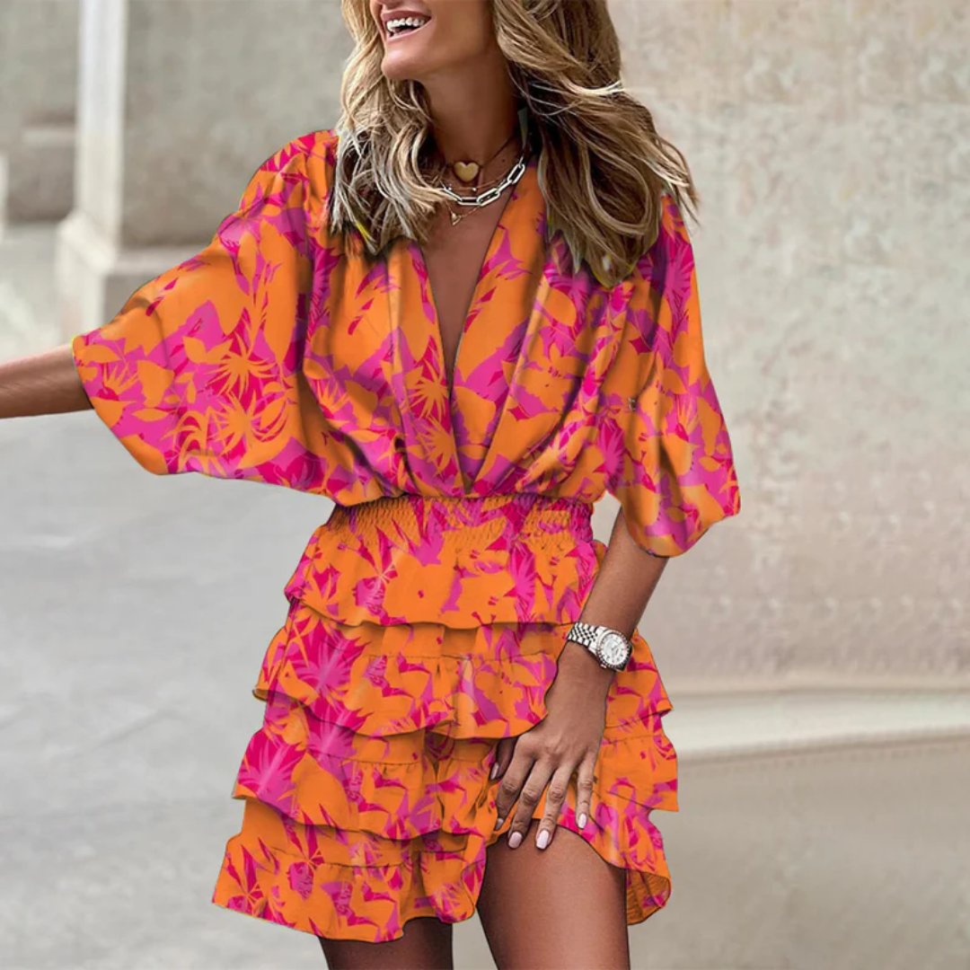 Frau in orange-pinkem Blumenkleid mit Rüschen, lächelnd, modisch, Sommermode, draußen.