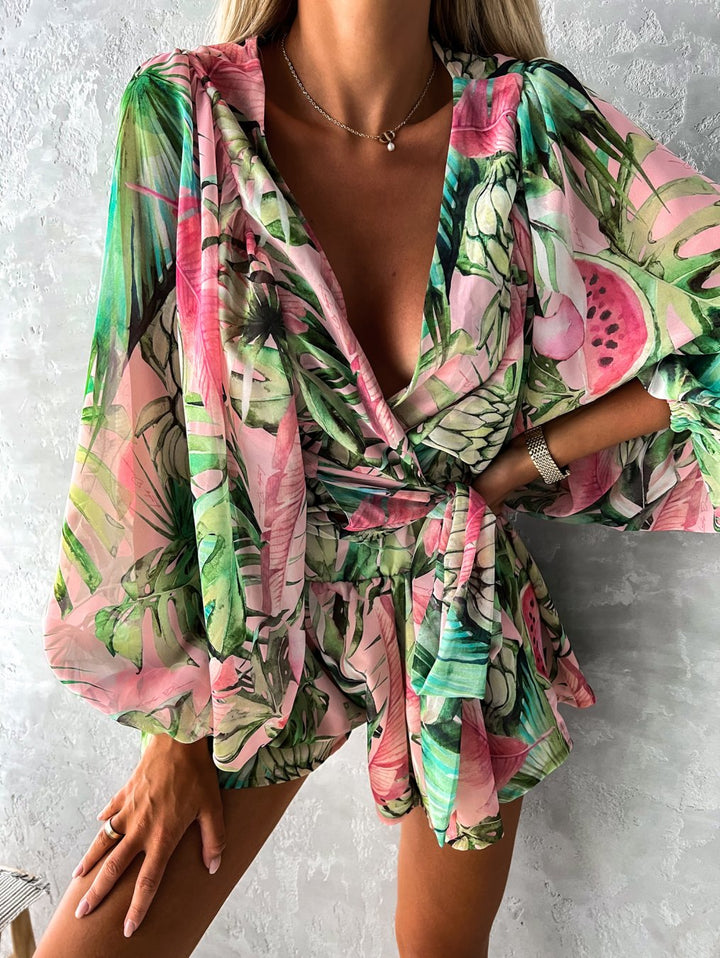 Frau in grün-rosa Sommerkleid mit tropischem Muster, V-Ausschnitt, lange Ärmel.