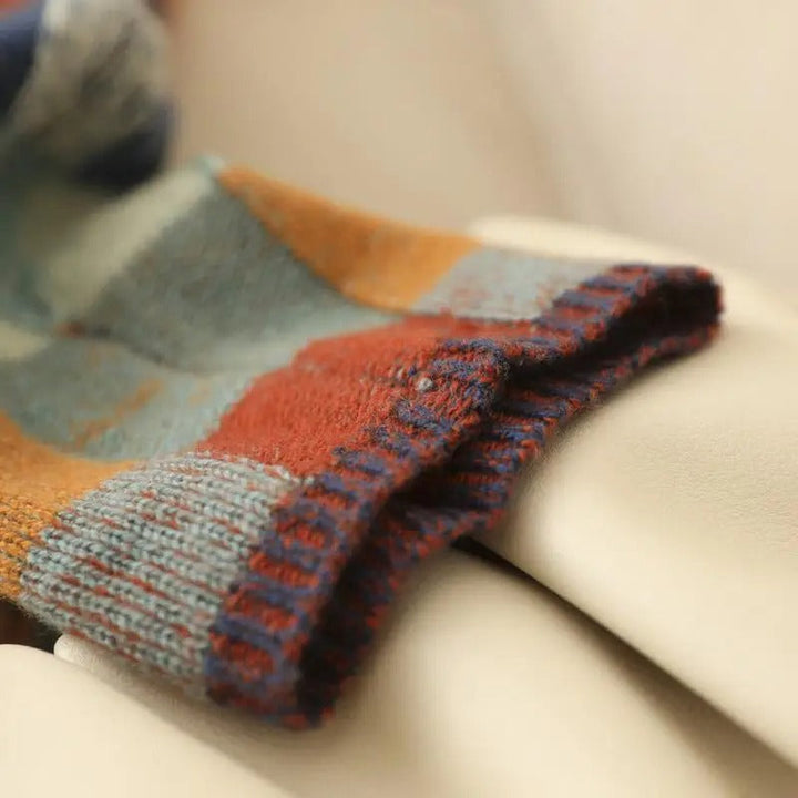 Bunte gestrickte Wollsocken, gestreift, warm, gemütlich, Herbstmode, auf beigem Hintergrund.