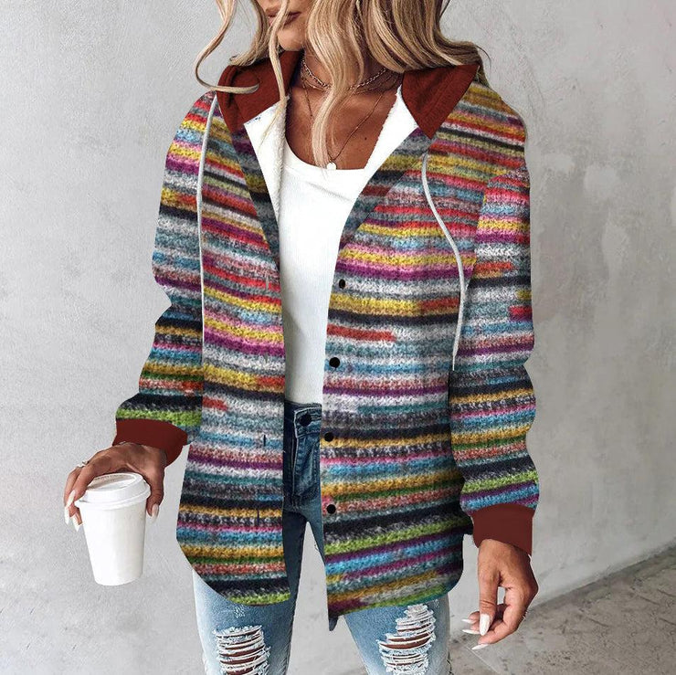 Frau in bunter gestreifter Strickjacke, weiße Bluse, zerrissene Jeans, hält Kaffeebecher.