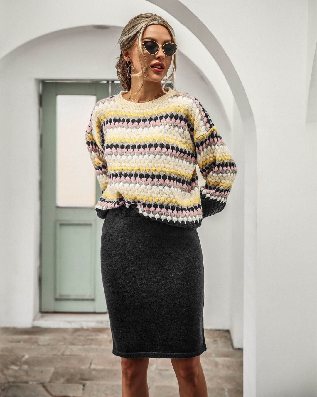 Frau in gestreiftem Pullover und grauem Rock, modisch, draußen, Sonnenbrille, lässiger Stil.