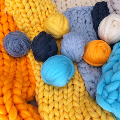 Bunte Wollknäuel und Strickdecken, gelb, blau, creme, ideal für Handarbeiten und Dekoration.