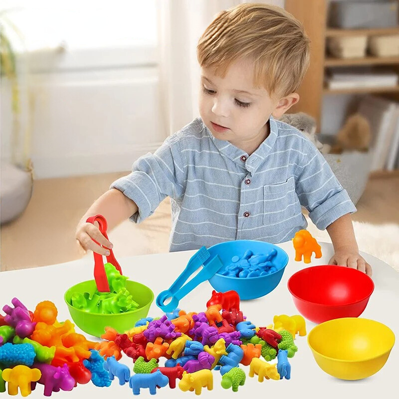 Kleinkind spielt mit bunten Tierfiguren und Schalen, Lernspielzeug, motorische Fähigkeiten.