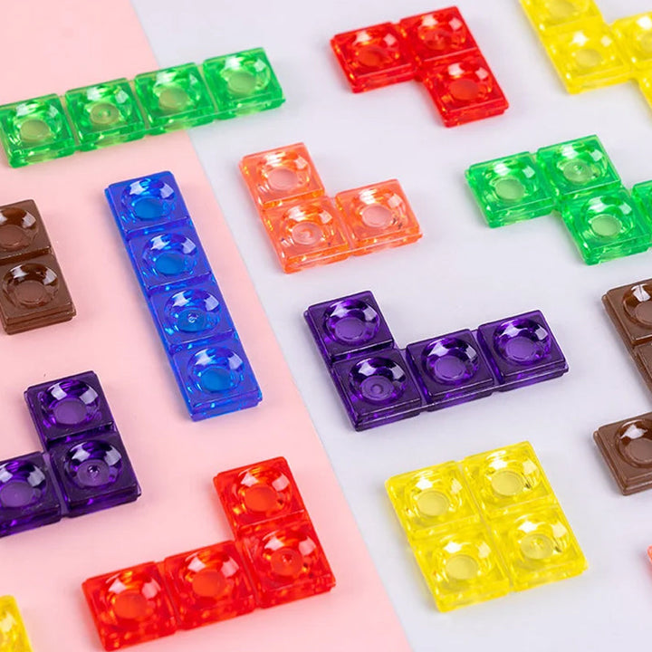 Bunte, transparente Bausteine in Tetris-Form auf weißem und rosa Hintergrund.