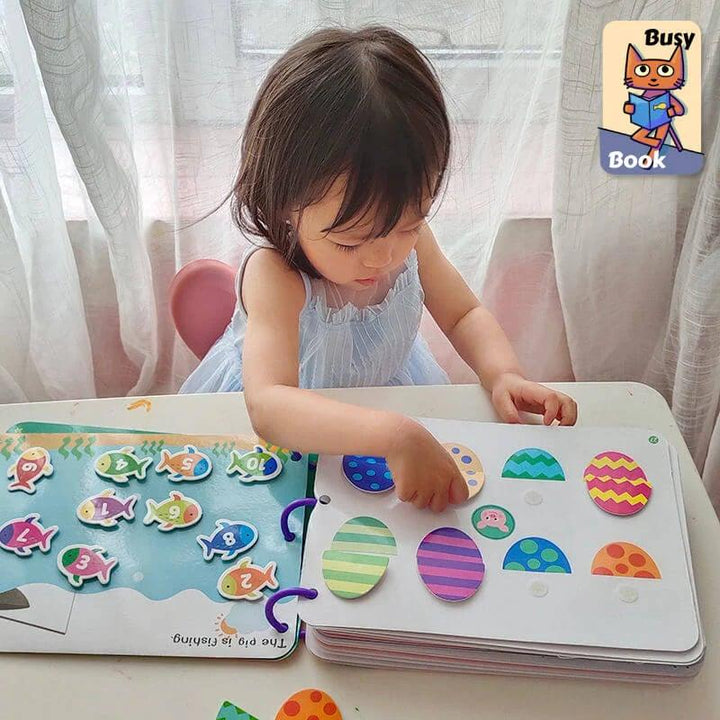 Kleinkind spielt mit Busy Book, Lernbuch für Kinder, farbenfrohe Formen, pädagogisches Spielzeug.