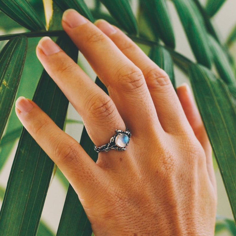 Hand mit Silberring und Mondstein, Schmuck, Natur, Boho-Stil, Damenmode, Nahaufnahme.