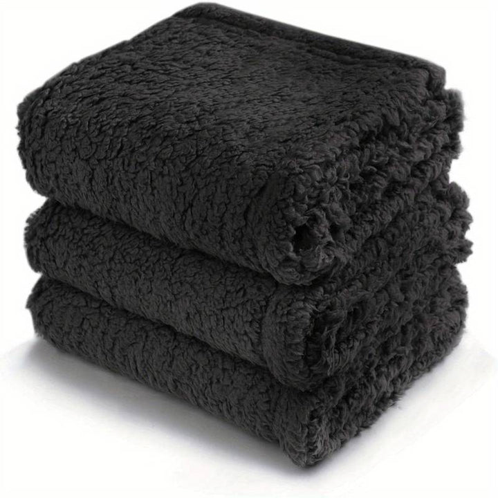 Dunkle, flauschige Fleece-Decke, gestapelt, weich, warm, ideal für Sofa oder Bett.