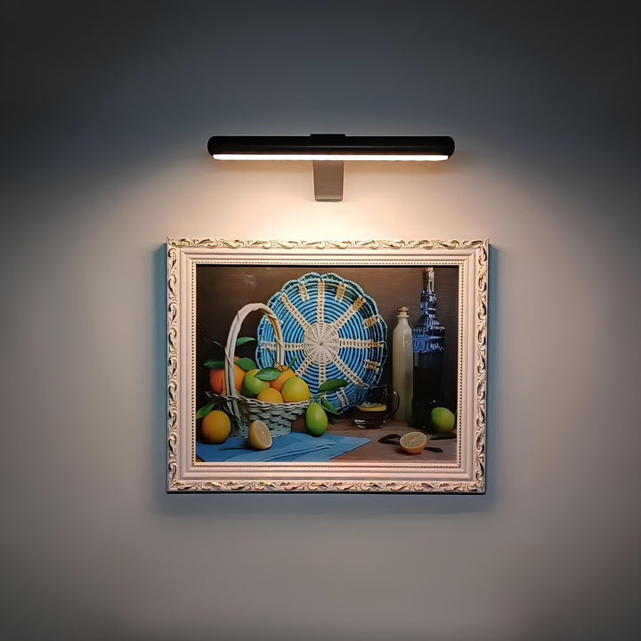Gemälde mit Obstkorb, Zitronen, Flasche und blauem Fächer, beleuchtet, im dekorativen Rahmen.