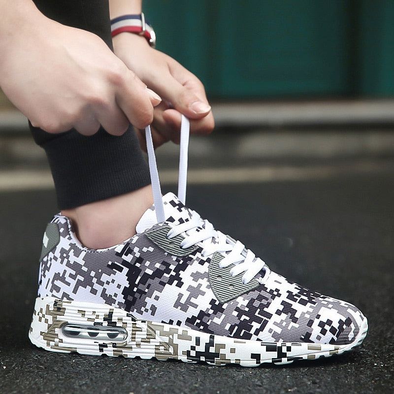 Person bindet Schnürsenkel von schwarz-weißen Camouflage-Sneakern auf Asphalt.