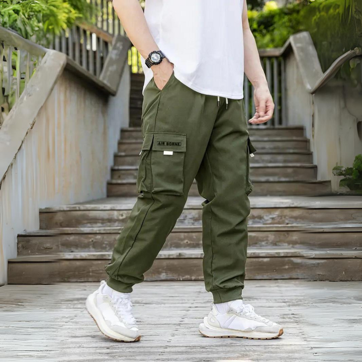Mann in olivgrüner Cargohose auf Treppe, lässiger Stil, Outdoor-Mode, Herrenhose.