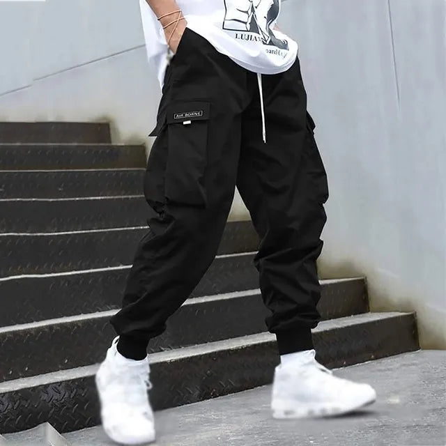 Schwarze Herren-Cargo-Jogginghose mit Taschen, Streetwear, Hip-Hop-Stil, Treppe, weiße Sneaker.