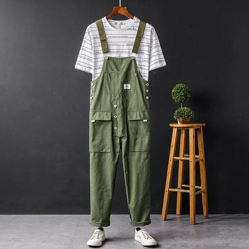 Grüne Herren-Latzhose mit Cargo-Taschen, lässig, Sommermode, auf Holzstuhl.