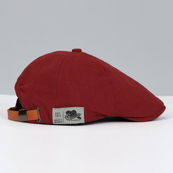 Rote Schiebermütze aus Baumwolle mit verstellbarem Lederriemen, modisches Accessoire.