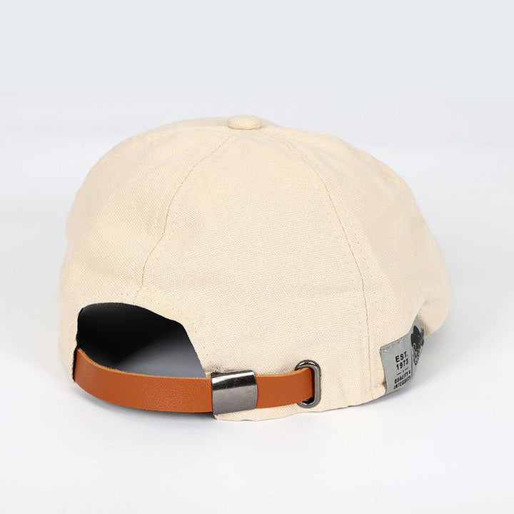 Beige Schiebermütze aus Baumwolle mit braunem Lederriemen, stilvoll und verstellbar.