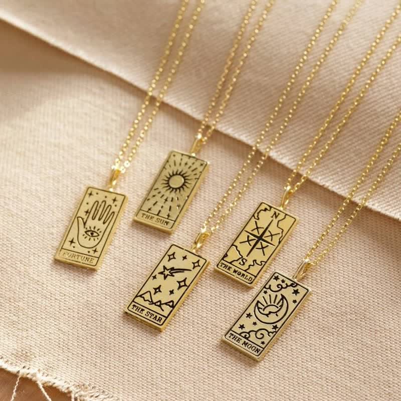 Fünf goldene Tarot-Anhänger auf Ketten, mit Symbolen: Sonne, Mond, Stern, Welt, Schicksal.