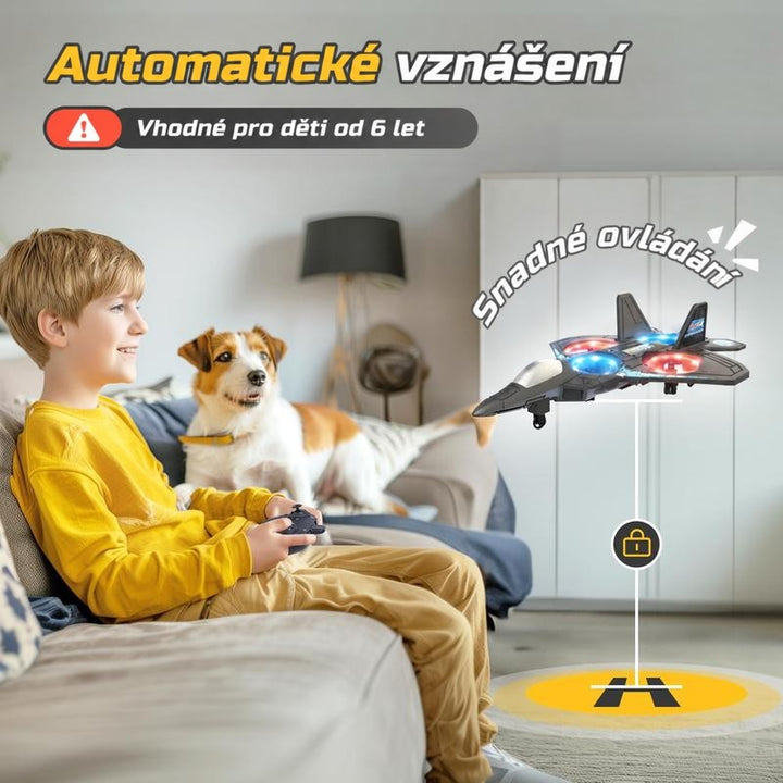 Usměvavý chlapec na pohovce ovládá ovladačem vznášející se letadlo s LED světly, vedle sedí pes. 6
