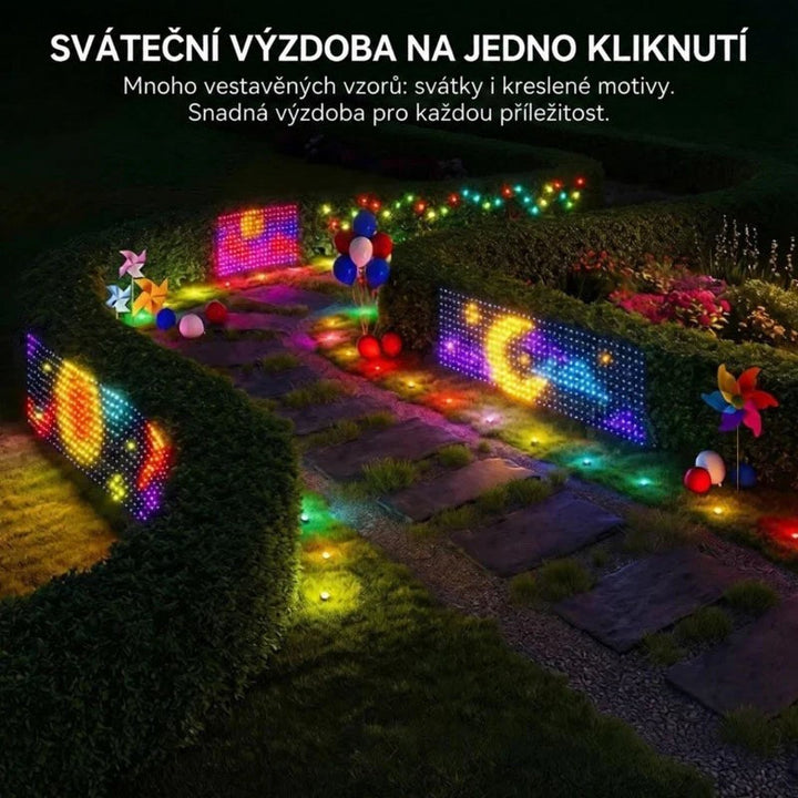 Několik světelných panelů s barevnými vzory rozmístěných v noční zahradě mezi živými ploty u chodníku 7