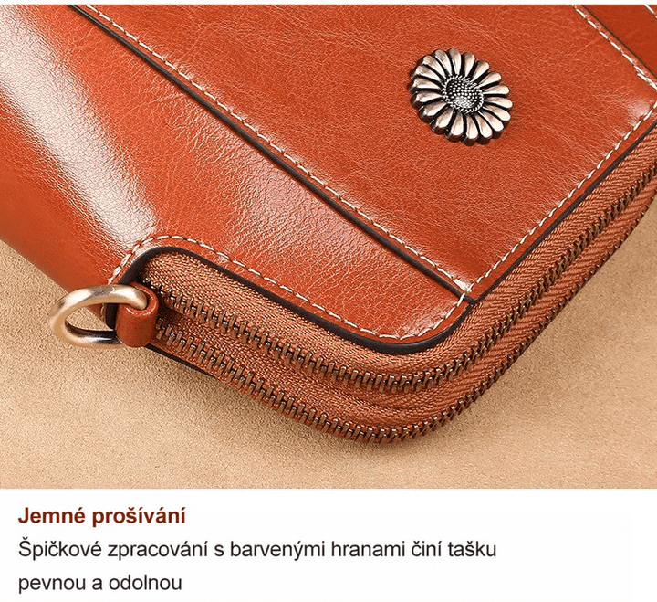 Detail rohu tašky s ozdobou, jemným prošíváním, zipem a kovovým kroužkem 16
