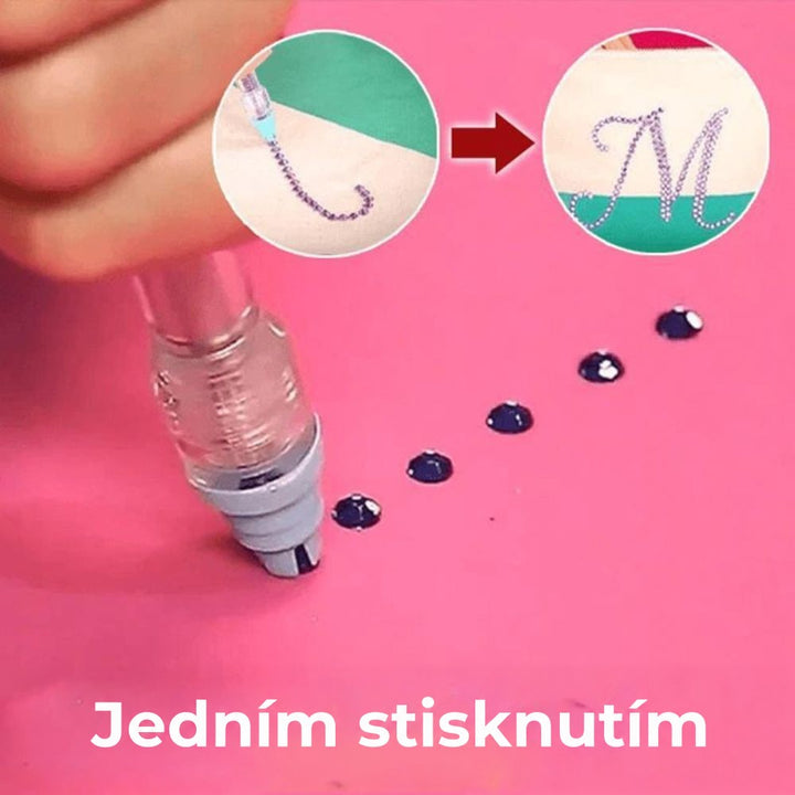 Pero s tlačítkem bere z růžového podkladu tmavé kamínky, v kruzích vzniká písmeno ze kamínků 3