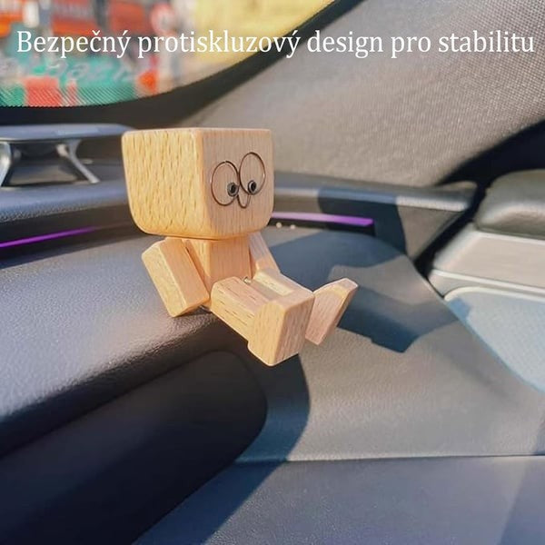 Figurka s kulatýma očima sedí na palubní desce auta, nohy opřené o hranu, aby se nesesunula. 12