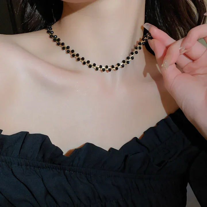 Frau trägt schwarzes Perlenhalsband, elegantes Schmuckstück, schwarzes Kleid, Abendmode.