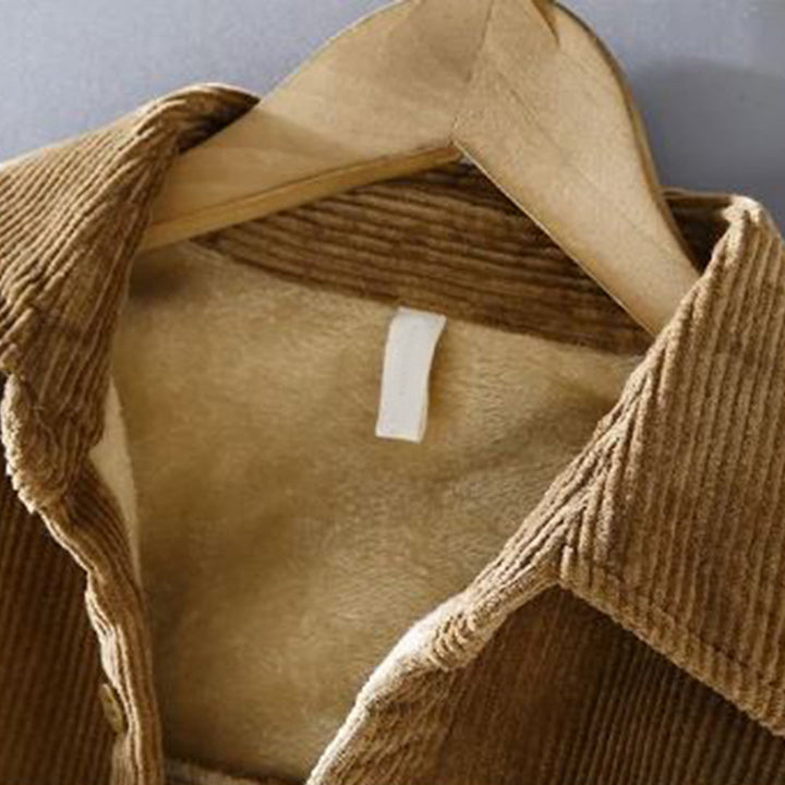 Braune Cordjacke mit Fellfutter auf Holzkleiderbügel, modische Herbstbekleidung.
