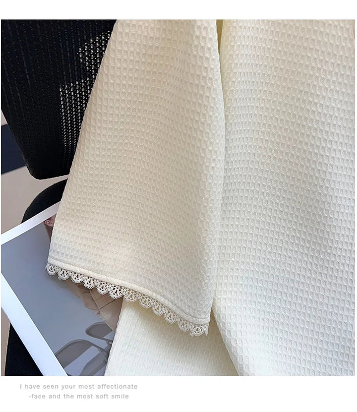 Cremefarbener Waffel-Strickstoff mit Spitzenrand auf schwarzem Stuhl, elegantes Textildesign.