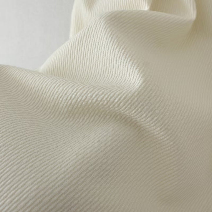 Cremefarbener Baumwollstoff mit feiner Rippstruktur, ideal für Bekleidung und Heimtextilien.