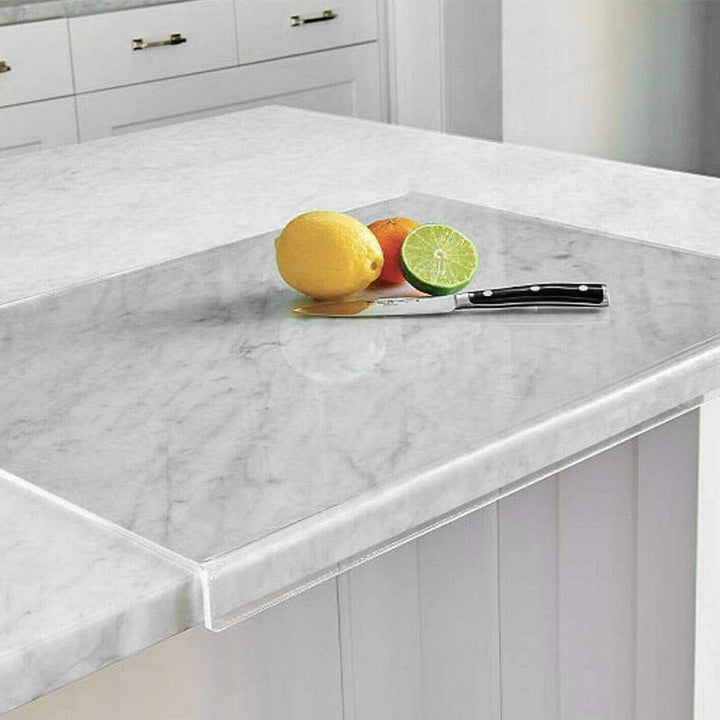 Glas-Schneidebrett auf Marmorarbeitsplatte mit Zitrone, Limette, Messer in moderner Küche.