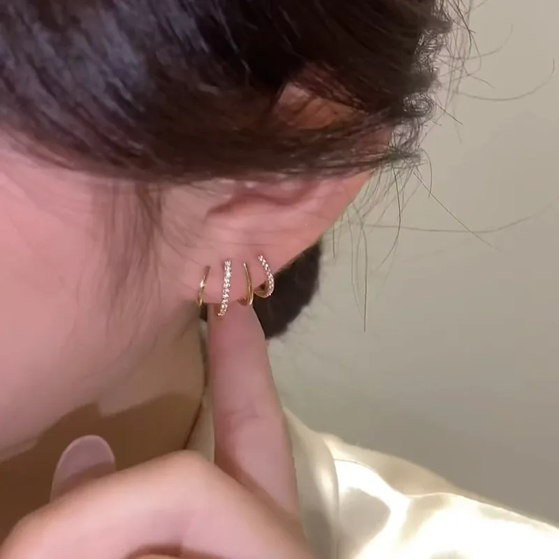 Detail čtyřramenné náušnice v uchu ze strany, modelka na ni ukazuje prstem 3