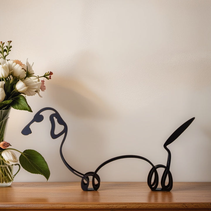 Dackel-Skulptur aus Metall, schwarz, auf Holzregal neben Blumenstrauß, moderne Deko.
